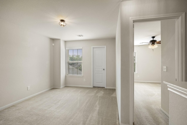 empty room featuring baseboards, ceiling fan, light carpet, and visible vents