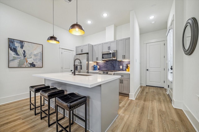kitchen featuring stainless steel appliances, a sink, gray cabinetry, baseboards, and recessed lighting