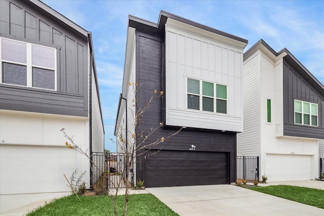 contemporary house with an attached garage, board and batten siding, driveway, and fence
