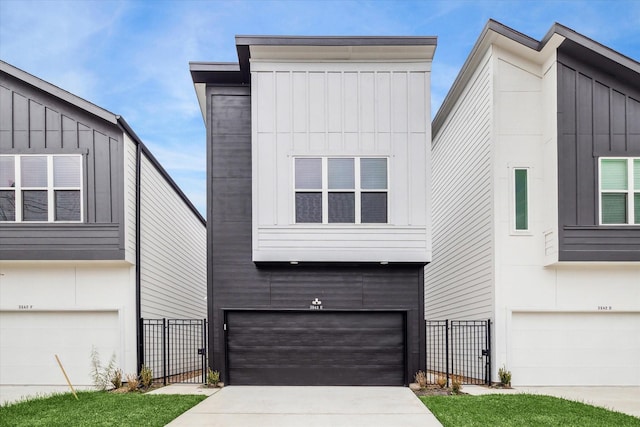 contemporary house with an attached garage, a gate, fence, driveway, and board and batten siding