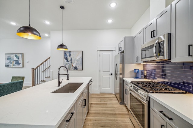 kitchen with stainless steel appliances, a sink, light wood-style flooring, tasteful backsplash, and recessed lighting