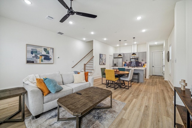 living room with a ceiling fan, baseboards, stairway, recessed lighting, and light wood-style flooring