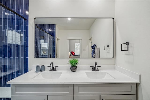 bathroom with tiled shower and double vanity