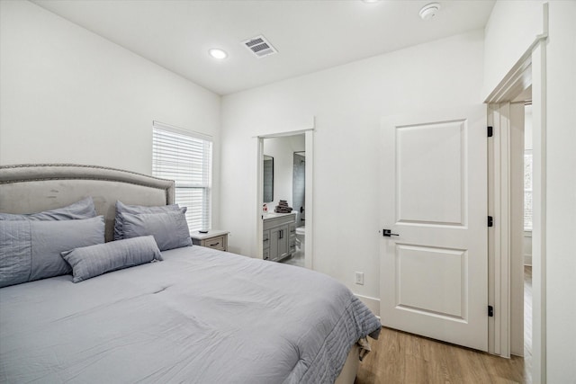 bedroom with light wood-type flooring, recessed lighting, and ensuite bathroom