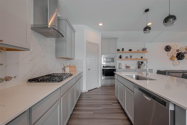 kitchen featuring wall chimney range hood, light countertops, a sink, gray cabinetry, and stainless steel appliances