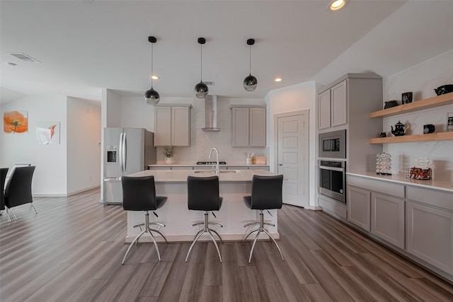kitchen with decorative backsplash, gray cabinets, light countertops, stainless steel appliances, and wall chimney exhaust hood