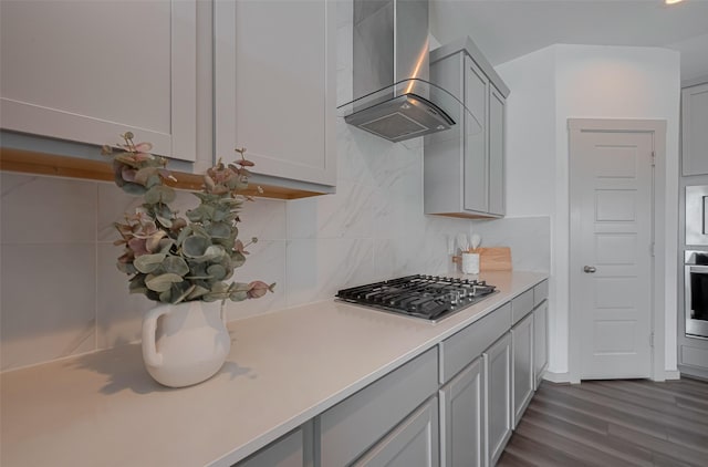 kitchen featuring wall chimney range hood, gray cabinets, tasteful backsplash, light countertops, and stainless steel appliances