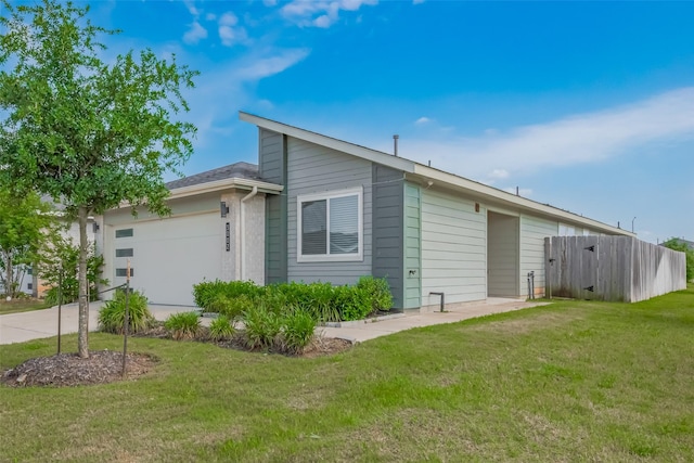 view of side of home with a lawn, a garage, fence, and driveway