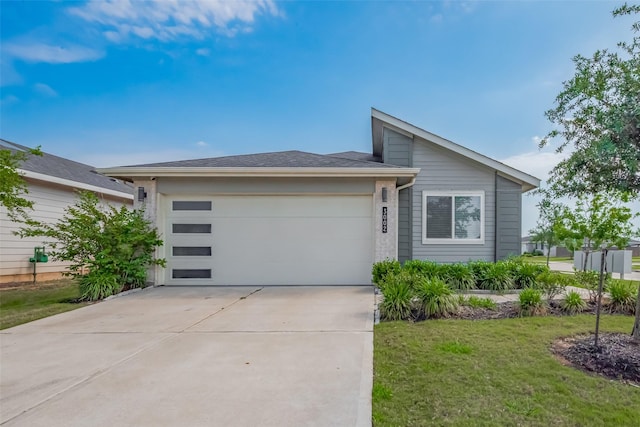 view of front of house with an attached garage, a front lawn, and concrete driveway