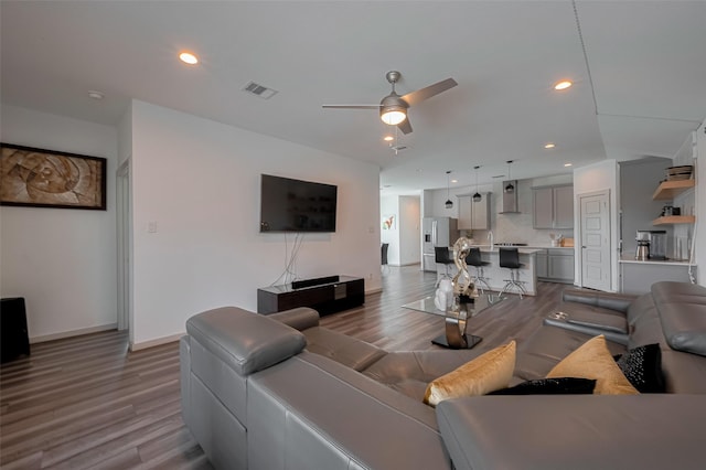 living room featuring ceiling fan, visible vents, and wood finished floors