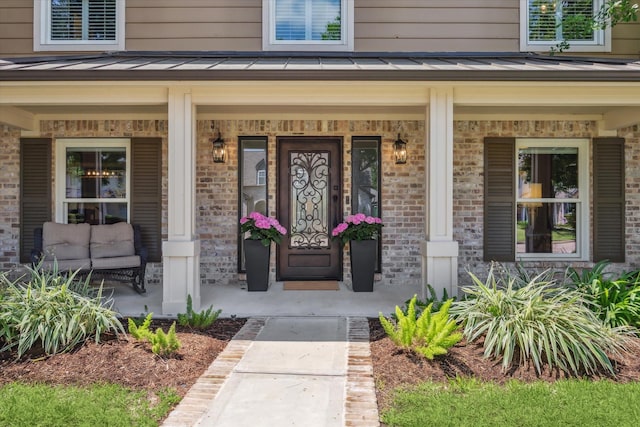 doorway to property featuring covered porch and a standing seam roof