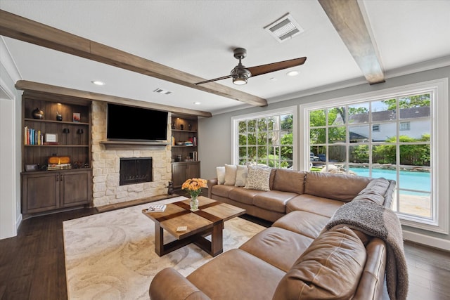 living area featuring visible vents, ceiling fan, a wealth of natural light, and beamed ceiling