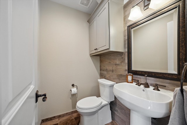 bathroom with visible vents, toilet, baseboards, tasteful backsplash, and a sink