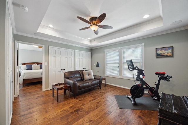 exercise room featuring crown molding, recessed lighting, a raised ceiling, hardwood / wood-style flooring, and a ceiling fan