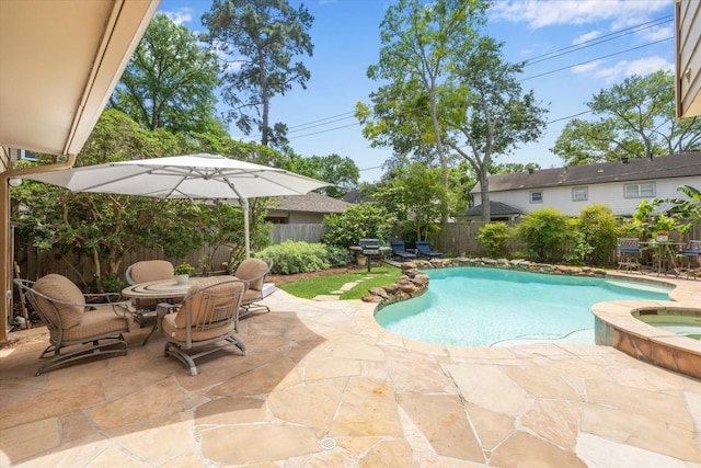 view of swimming pool with a patio, a fenced backyard, a pool with connected hot tub, and outdoor dining space