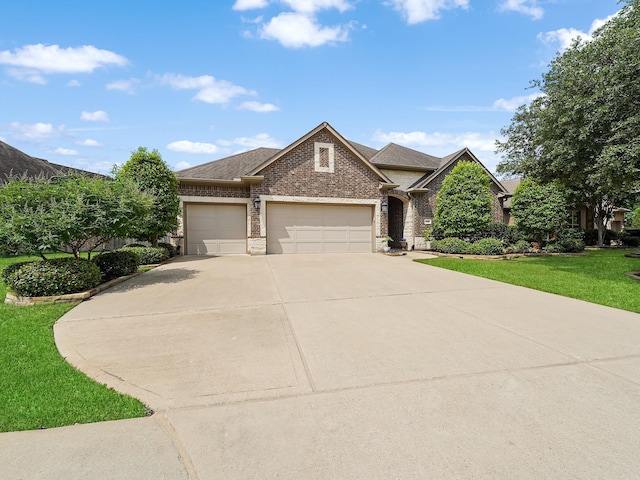 view of front of property with a front yard, roof with shingles, brick siding, an attached garage, and driveway