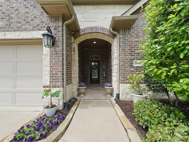 view of exterior entry with brick siding and an attached garage