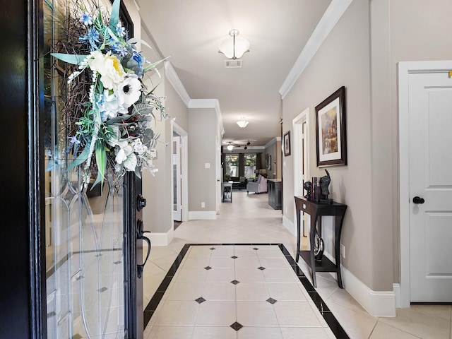 foyer entrance with crown molding, baseboards, visible vents, and light tile patterned floors