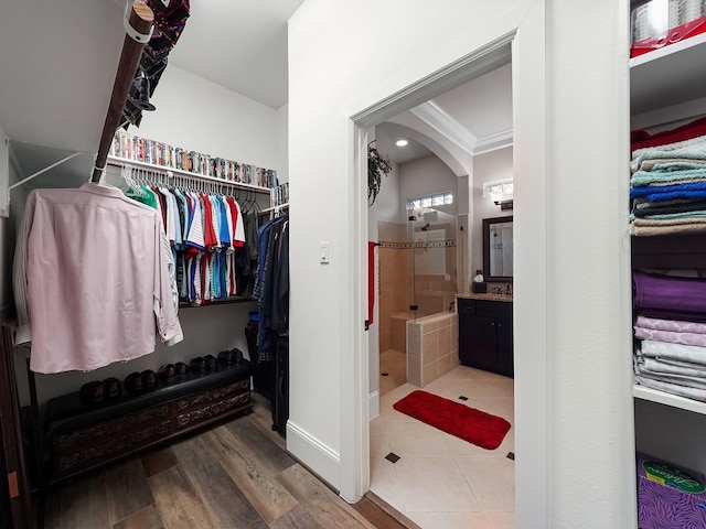 walk in closet with arched walkways and wood finished floors