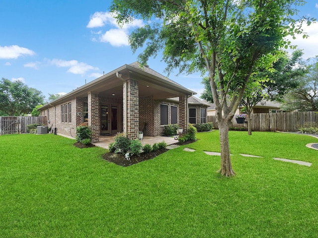 rear view of property with a lawn, a fenced backyard, a patio area, and brick siding
