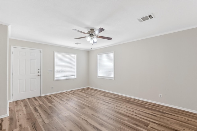 spare room featuring a ceiling fan, visible vents, ornamental molding, and light wood-type flooring