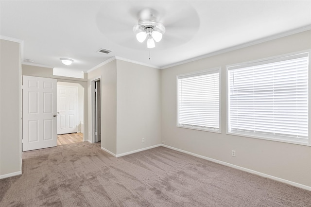 unfurnished room with visible vents, crown molding, baseboards, ceiling fan, and carpet flooring