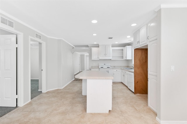 kitchen with visible vents, a kitchen island, light countertops, white cabinets, and electric stove