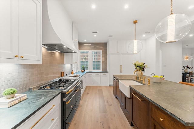 2530 Stanmore Dr, Houston, TX 77019 - kitchen featuring range with gas stovetop, custom exhaust hood, a sink, light wood-type flooring, and white cabinetry