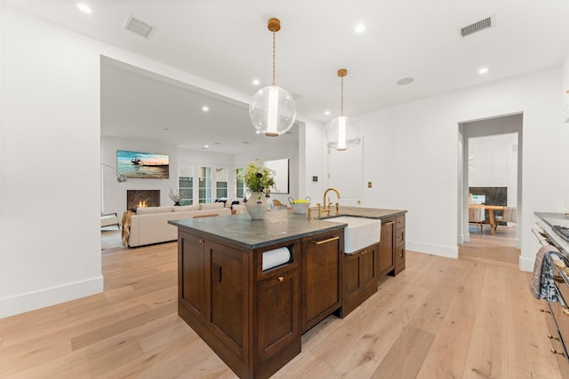 2530 Stanmore Dr, Houston, TX 77019 - kitchen featuring a warm lit fireplace, a sink, dark countertops, recessed lighting, and light wood-style flooring