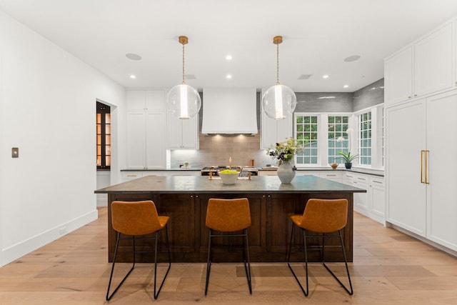 2530 Stanmore Dr, Houston, TX 77019 - kitchen featuring custom exhaust hood, light wood-style floors, dark countertops, backsplash, and recessed lighting