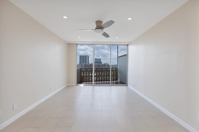 unfurnished room featuring baseboards, a ceiling fan, recessed lighting, and expansive windows