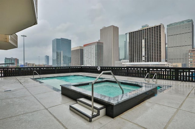 view of pool featuring a view of city, a hot tub, and a patio area