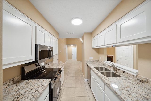 kitchen featuring visible vents, appliances with stainless steel finishes, a sink, light tile patterned floors, and white cabinets