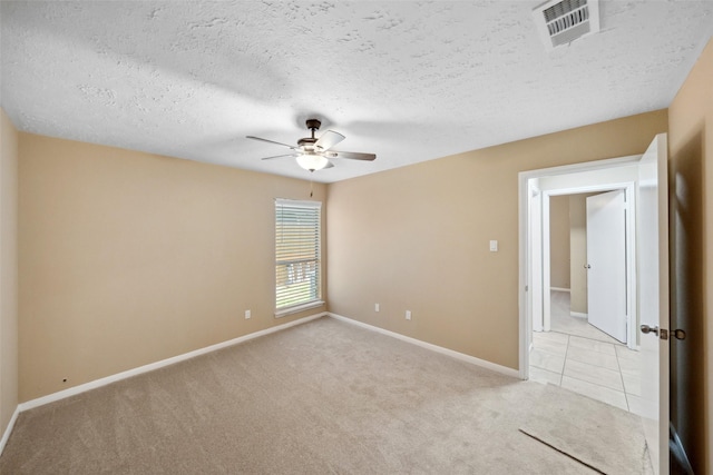 empty room featuring ceiling fan, a textured ceiling, visible vents, baseboards, and light carpet