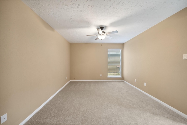 carpeted spare room featuring baseboards, ceiling fan, and a textured ceiling