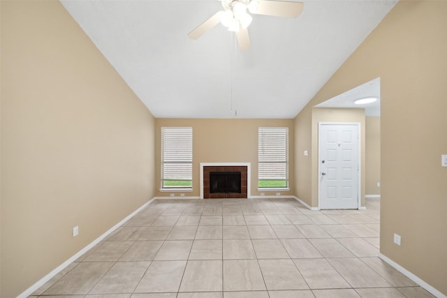 unfurnished living room with light tile patterned flooring, baseboards, ceiling fan, a tiled fireplace, and vaulted ceiling