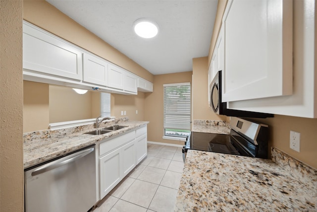 kitchen featuring light stone counters, a sink, white cabinets, and stainless steel appliances