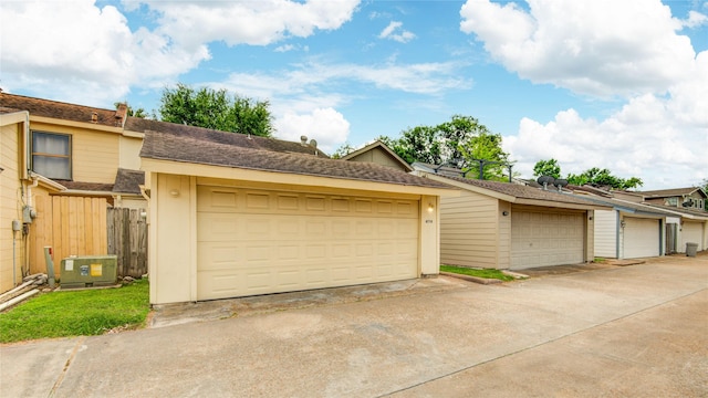 exterior space with fence, central AC, and a garage