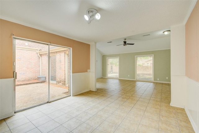 spare room with crown molding, light tile patterned flooring, ceiling fan, and a wainscoted wall