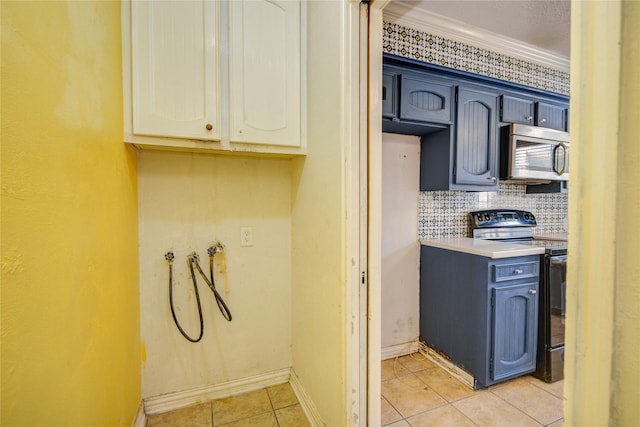 kitchen with decorative backsplash, black range with electric cooktop, light countertops, stainless steel microwave, and light tile patterned floors