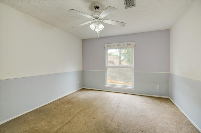 carpeted spare room featuring visible vents, a ceiling fan, and baseboards