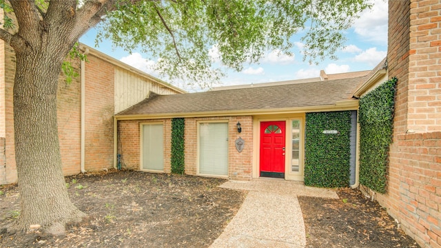 view of front of house with brick siding and roof with shingles