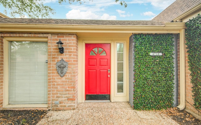 property entrance with brick siding and a shingled roof