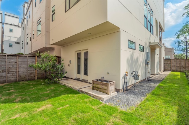 back of property featuring a yard, fence, and stucco siding
