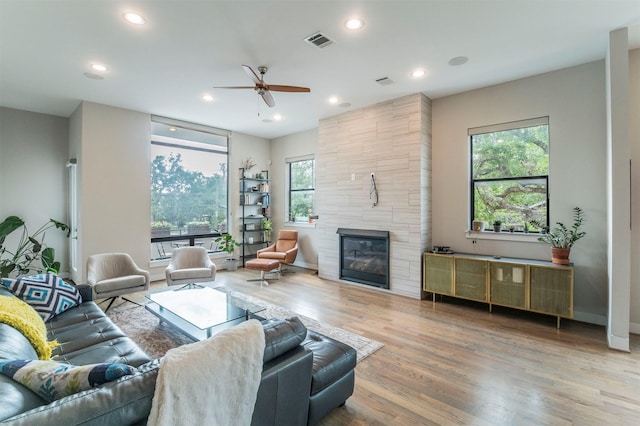 living room with plenty of natural light, ceiling fan, wood finished floors, and a fireplace