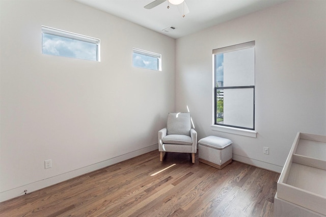 sitting room with a ceiling fan, baseboards, visible vents, and wood finished floors