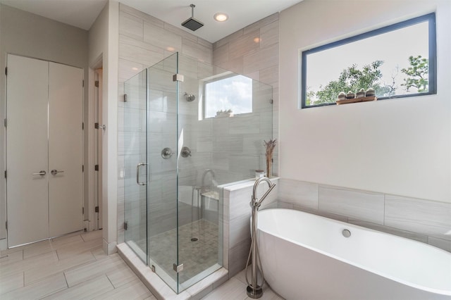 full bathroom featuring a soaking tub and a shower stall