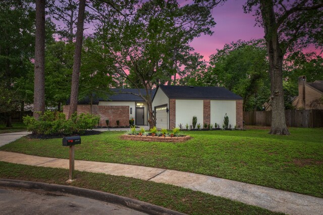 view of front of house with an attached garage, a front lawn, fence, and brick siding