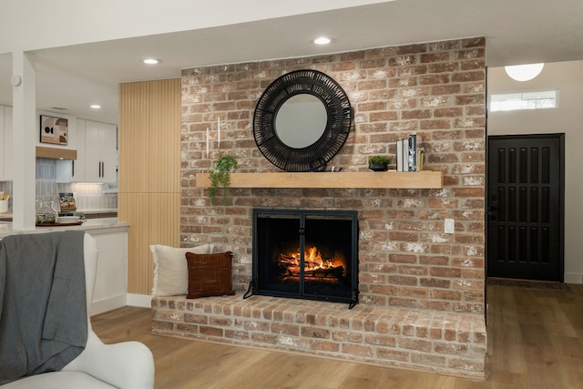 living area featuring recessed lighting, baseboards, wood finished floors, and a fireplace