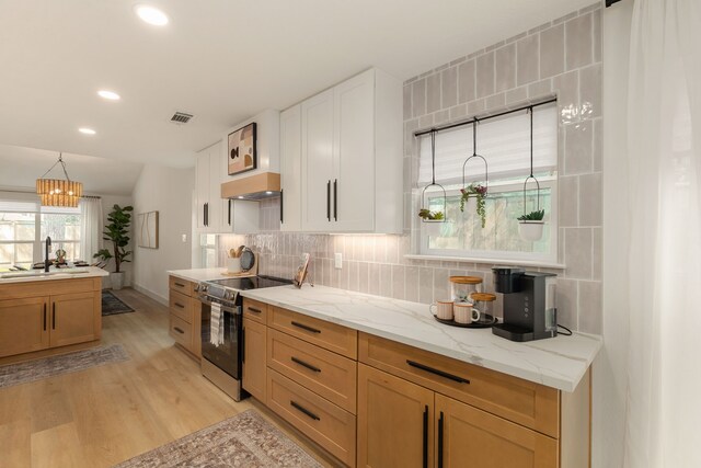 kitchen featuring exhaust hood, visible vents, stainless steel range with electric stovetop, a sink, and light wood finished floors